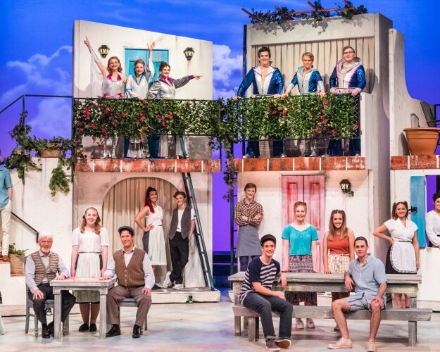 Large number of cast members posing for photo on set of Mamma Mia.