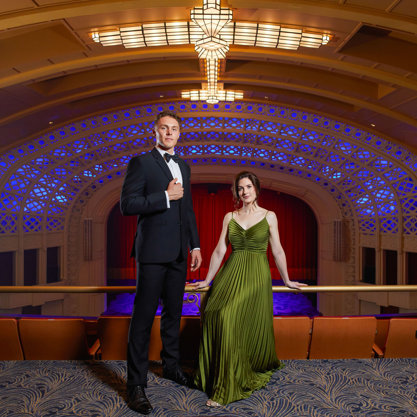 Gabriel Tiller standing on the Empire balcony in front of the lighted proscenium arch with Shannon Gralow 