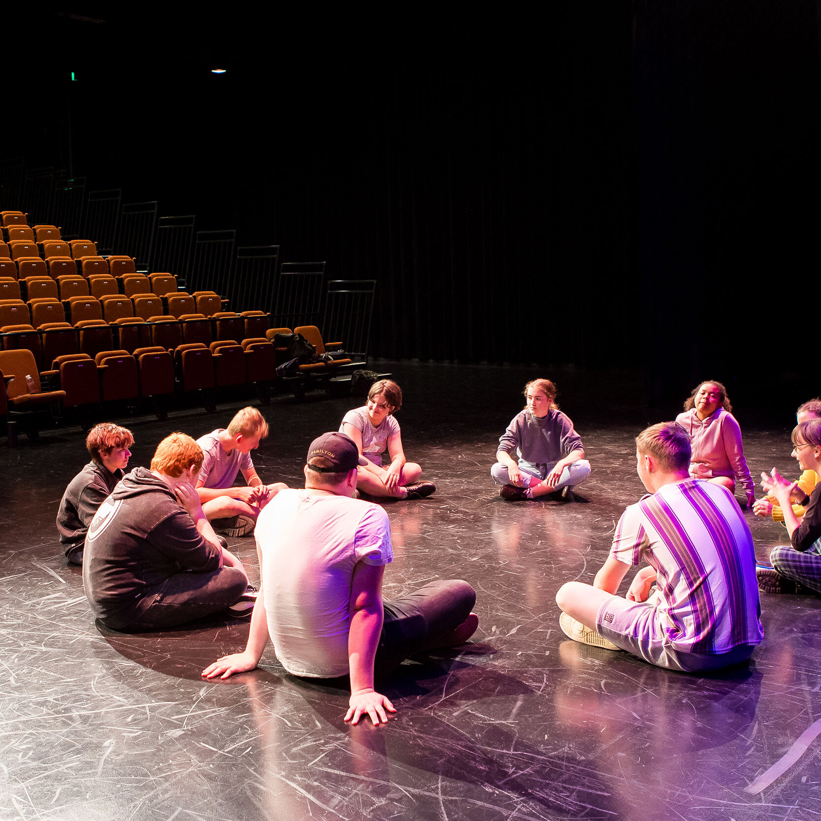 Young performers sitting on a stage in a circle