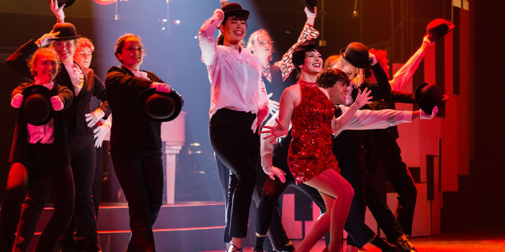 Actor portraying Liza Minnelli with a group of dancers performing a song in The Boy from Oz musical.
