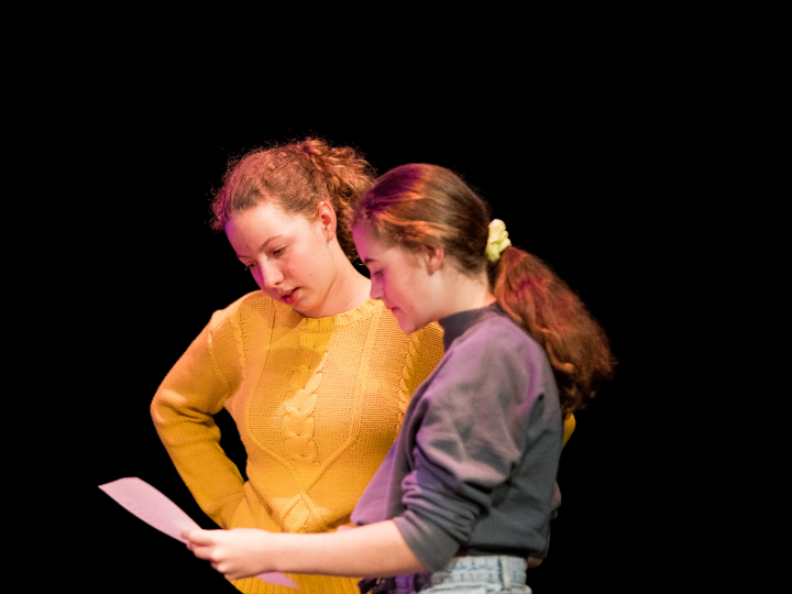 Two youth arts performers reviewing a script together. 