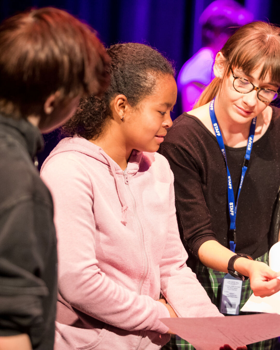 Two young people being handed script by staff.